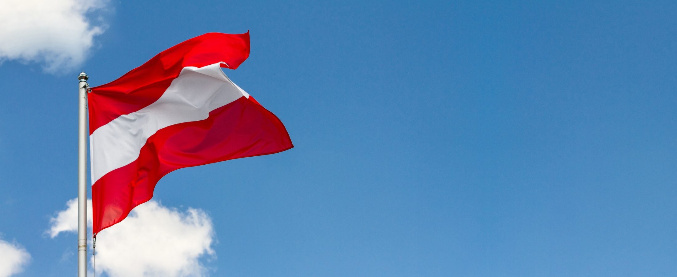 Bandeira da Áustria hasteada contra o céu azul