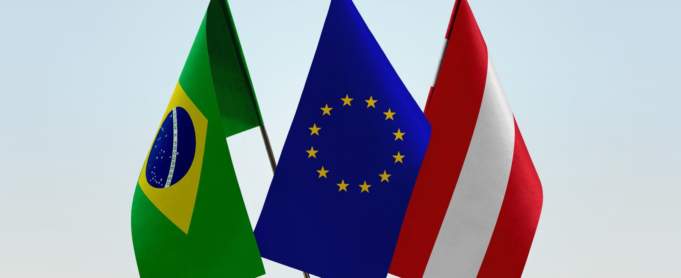Bandeiras do Brasil, da União Europeia e da Áustria lado a lado sobre uma mesa